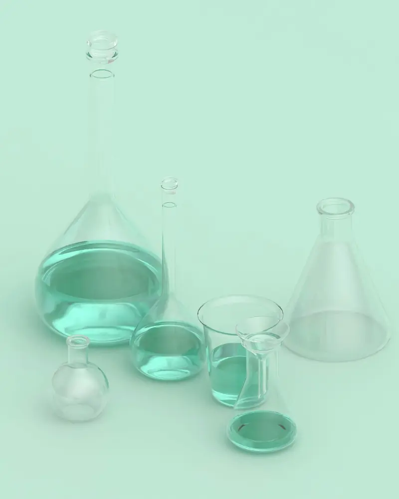 Matraces y vasos de laboratorio de cristal transparente sobre un fondo verde menta